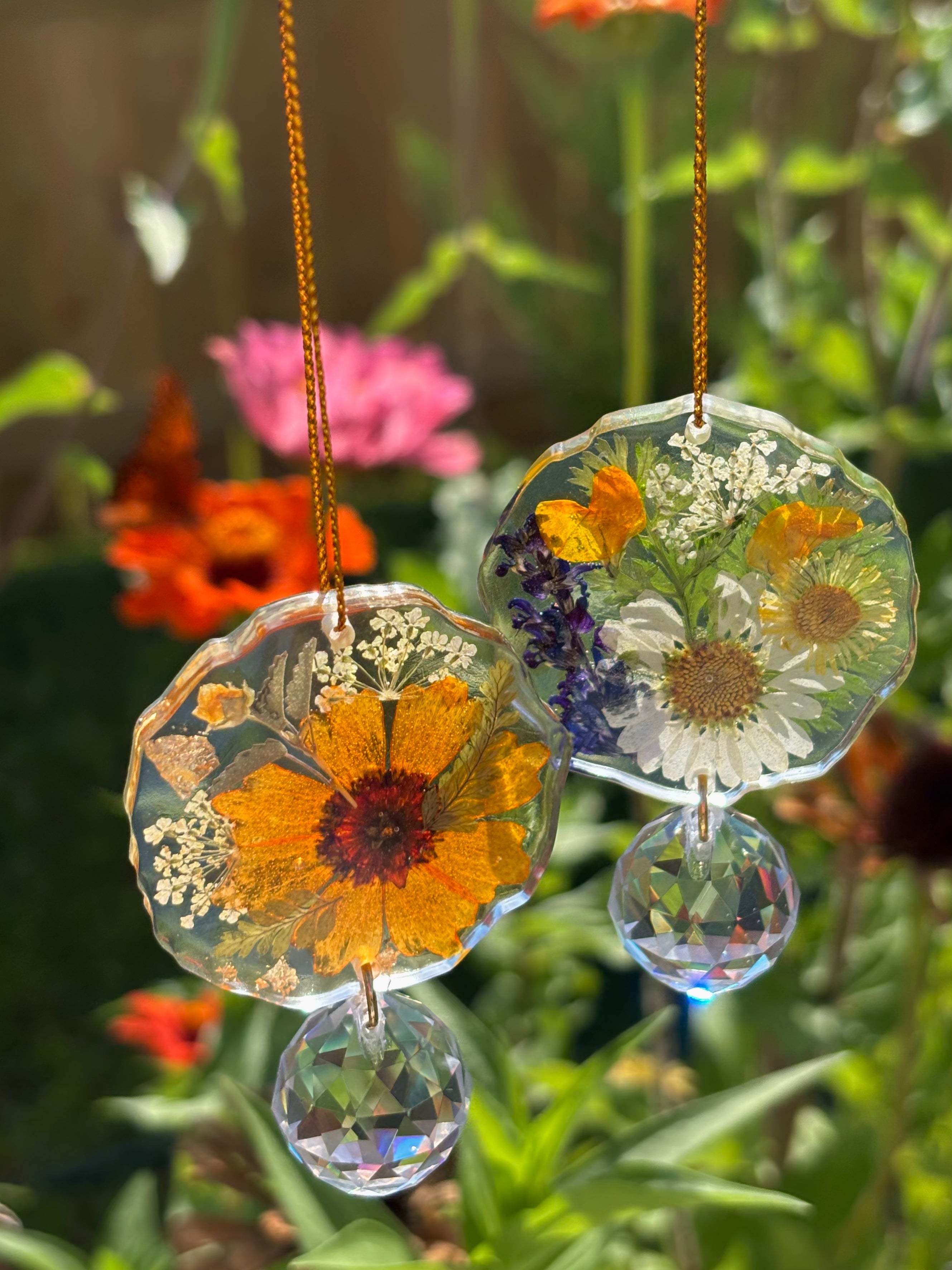 Decorative hanging with pressed flowers and crystals against a garden background